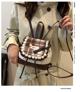 Detail of a mini backpack featuring cherry pattern lace and brown checkered flap design