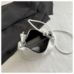 Interior view showing capacity of white leather dumpling bag with phone and earplugs