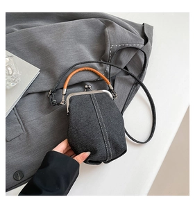 Detail of vintage denim bucket bag with leather handle and silver metal clasp closure