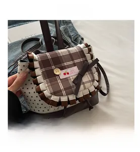 Detail of vintage school backpack featuring brown plaid flap with lace trim and bow knot