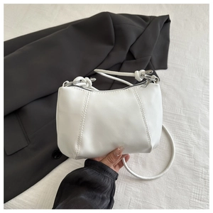 Detail of the white crossbody bag featuring vertical stitching and a silver metal zipper