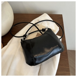 Detail of minimalist black glossy PU leather handbag with decorative vertical stitching and knots