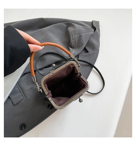 Detail view of mini kiss-lock denim bucket bag with circular handle and fabric lining