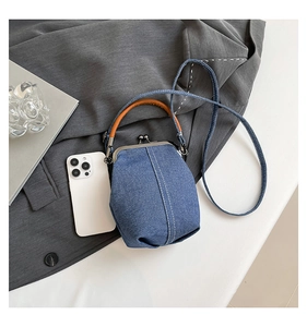 Detailed top view of denim bucket bag with metal clasp and brown leather handle