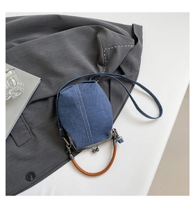 Detailed view of blue denim bucket bag with retro metal clasp and brown top handle