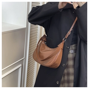 Detail of a dark brown half-moon hobo bag with adjustable leather strap and silver metal hardware