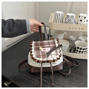 Détail d'un sac à dos à carreaux avec motif d'étoiles, ruban et étiquette cerise