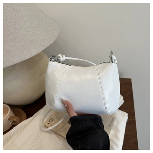 Detail of white dumpling bag with knotted handle and elegant gathered pleats on soft fabric