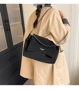 Detail of a black leather chain shoulder bag showing the fashion logo and matte finish