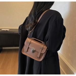 Rear view of a model wearing a brown vintage leather crossbody bag over a black coat