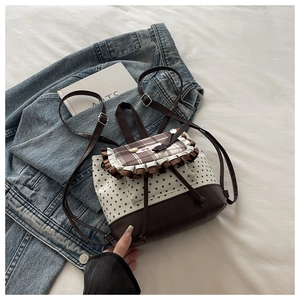 Détail d'un mini sac à dos en toile avec imprimé étoiles, rabat écossais et dentelle