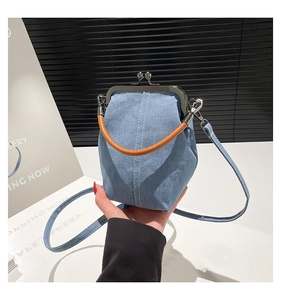 Detail of vintage blue denim shell bag showing white stitching and metal clasp closure