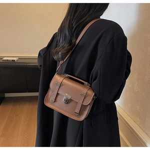 Detailed close-up of retro brown crossbody bag with metal twist lock and dual straps