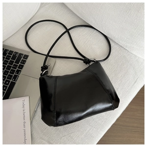 Close-up of black glossy dumpling bag with knot detail and silver metal buckle hardware
