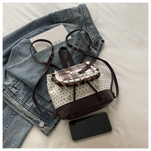 Detailed view of mini star print backpack with brown plaid flap and lace trim on fabric