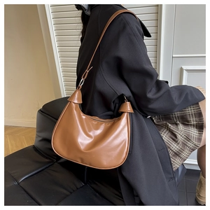 Detailed close-up of dark caramel half-moon hobo bag with adjustable shoulder strap and zipper