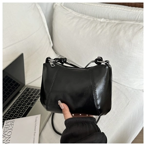 Close-up of minimalist black shoulder bag with stylish knotted strap and silver hardware