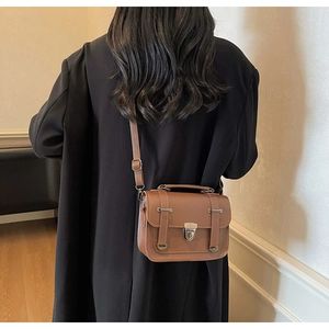 Brown vintage messenger bag with metal locks shown from a side-view on a female model