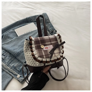 Detail of sweet plaid flap backpack with star pattern and cherry logo on bed setting
