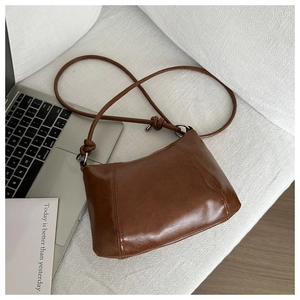 Detailed view of deep brown vintage leather crossbody bag with silver rings and knots