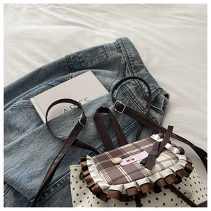 Detail of cute plaid backpack with brown star patterns, lace frills and cherry label