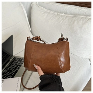 Detail of vintage brown PU leather handbag with side knot accents and metallic rings