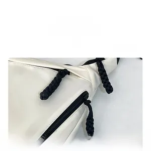 Detail view of white nylon tote bag with black braided rope zippers and utility pockets