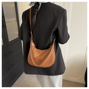 Caramel brown leather hobo bag worn over a black blazer, showing medium size and fit
