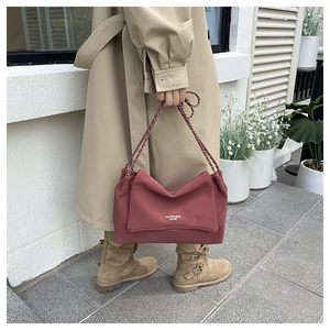 Detail of dark pink leather shoulder bag with silver metal chain and fashion text