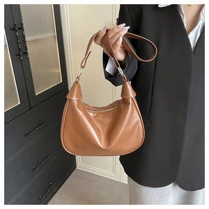 Detail of caramel crescent shoulder bag showing smooth leather texture and zip closure