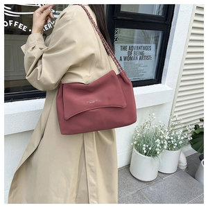 Detail of red leather shoulder bag with gold chain strap and elegant envelope flap design