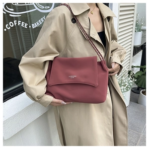 Close-up of matte dark red leather tote bag featuring a metal chain strap and logo
