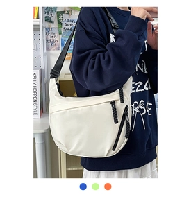 Close-up of a white crescent shoulder bag with black strap and zipper detail on a model