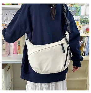 Detailed view of the large white crescent bag with black adjustable shoulder strap