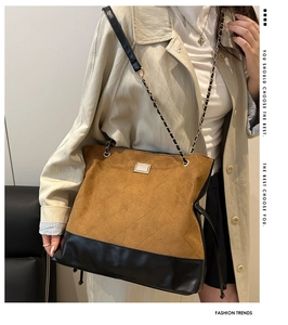 Detail of suede tote bag featuring diamond quilting and metal chain shoulder strap