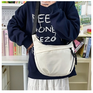 Detailed view of lightweight white nylon dumpling sling bag with adjustable black strap