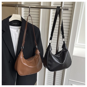 Detail of hobo shoulder bags in brown and black leather with silver metal rings