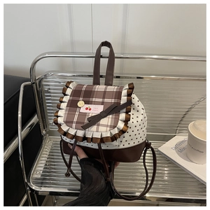 Close-up of brown plaid backpack with cherry patch, ruffles, and star print pattern