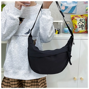 Detail of black nylon crescent bag featuring adjustable strap and woven zipper pull cord