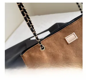 Close-up of brown suede tote bag featuring diamond quilt stitching and golden chain strap