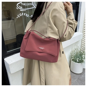 Detail of burgundy tote bag with leather chain strap and white printed fashion text
