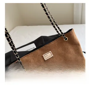 Detail of brown suede tote with diamond quilting, gold hardware, and chain strap