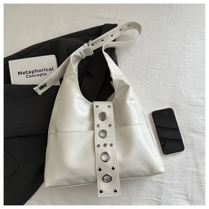 Detailed view of white hobo bag with silver metallic eyelets and studded shoulder strap