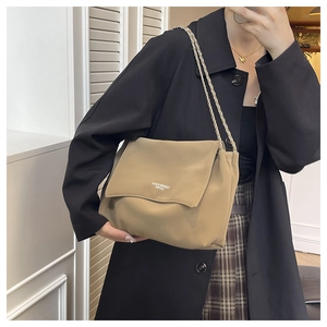 Side view of khaki leather tote bag with metal chain strap and embossed lettering