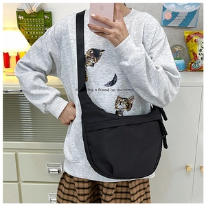 Close-up of black nylon crescent crossbody bag worn by model in casual daily setting