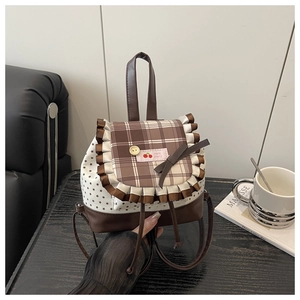 Detailed close-up of a vintage plaid backpack with cherry embroidery and lace trim details