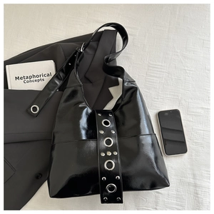 Detail of black hobo bag showing metallic silver eyelets and rivets on wide strap