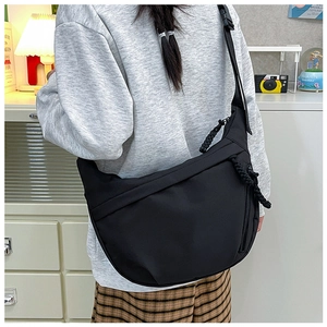 Detail view of black nylon crescent crossbody bag featuring adjustable strap and zip pocket