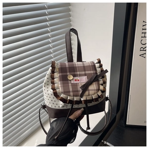 Detail of checkered backpack cover with lace ruffles, star prints and cherry embroidery