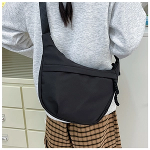 Rear view of a black minimalist crescent crossbody bag with nylon strap and woven detail